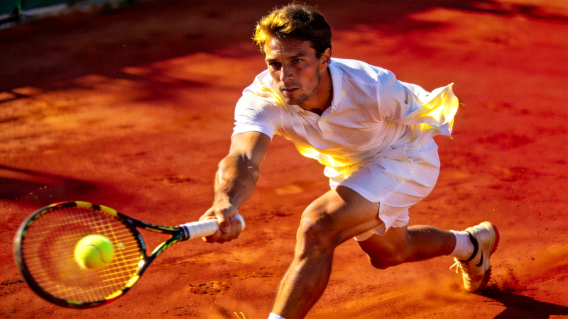 网球运动员在红土场上奋力挥拍击球的瞬间